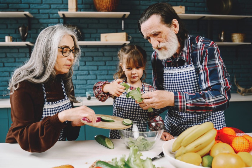 Grandparents cooking a healthy meal with their granddaughter